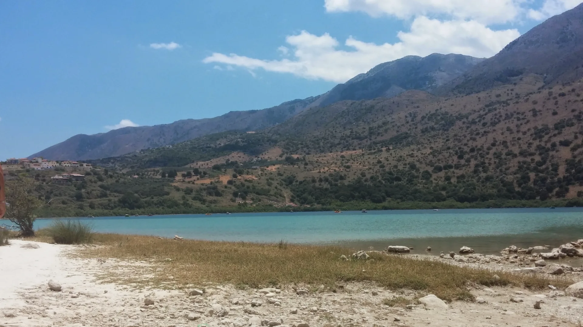 View across Lake Kournas with blue-green water and mountains behind it