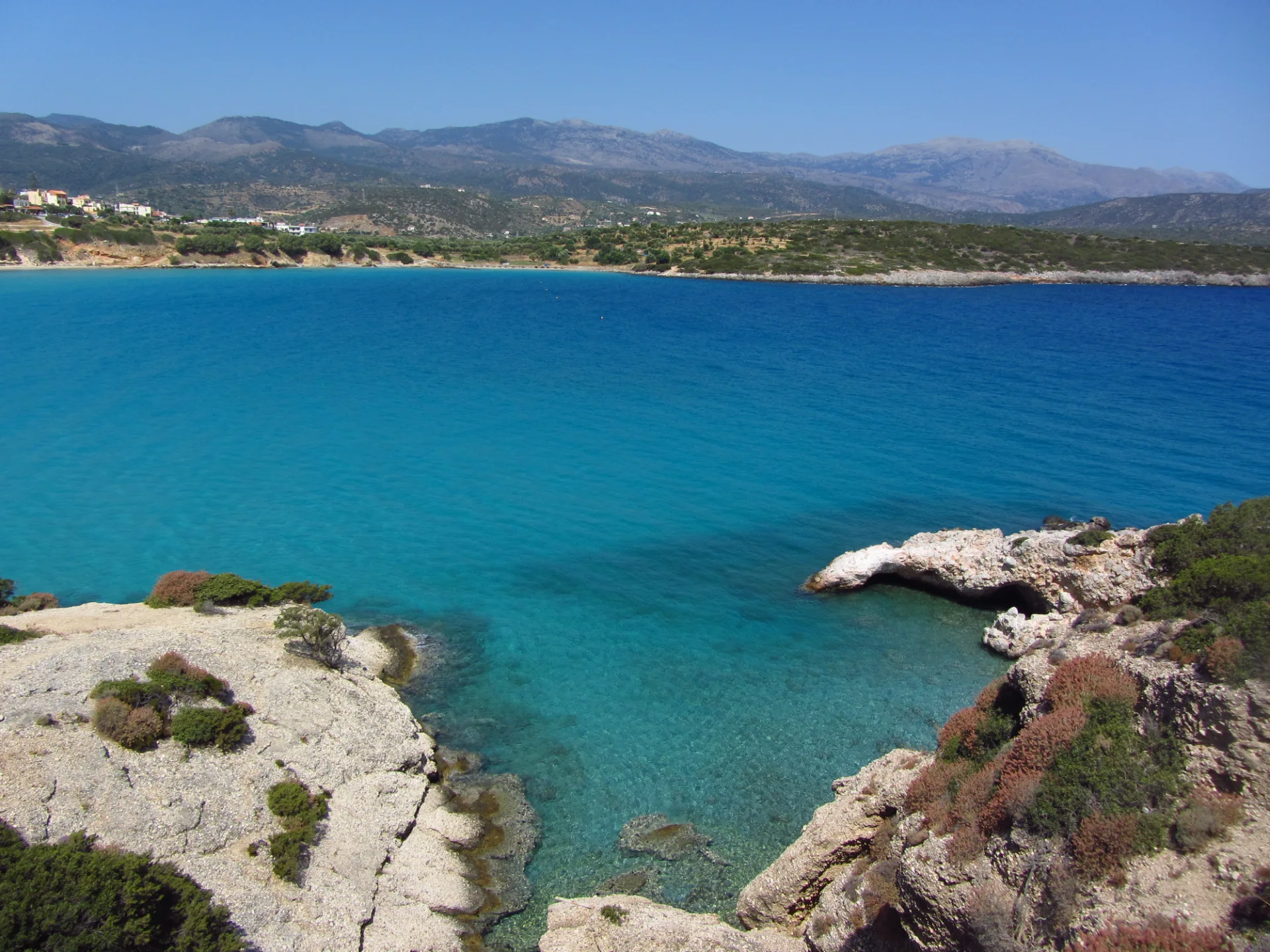 View across the clear turquoise water at Voulisma Beach toward the mountains of eastern Crete