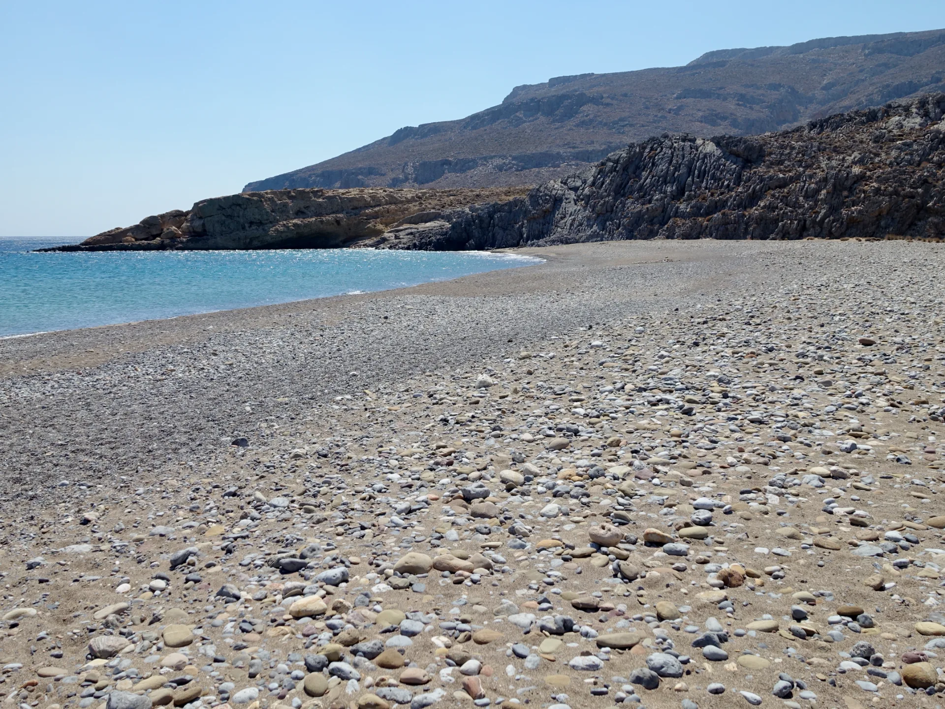 Karoumes Beach on Crete's remote east coast with a pebble shore and arid landscape