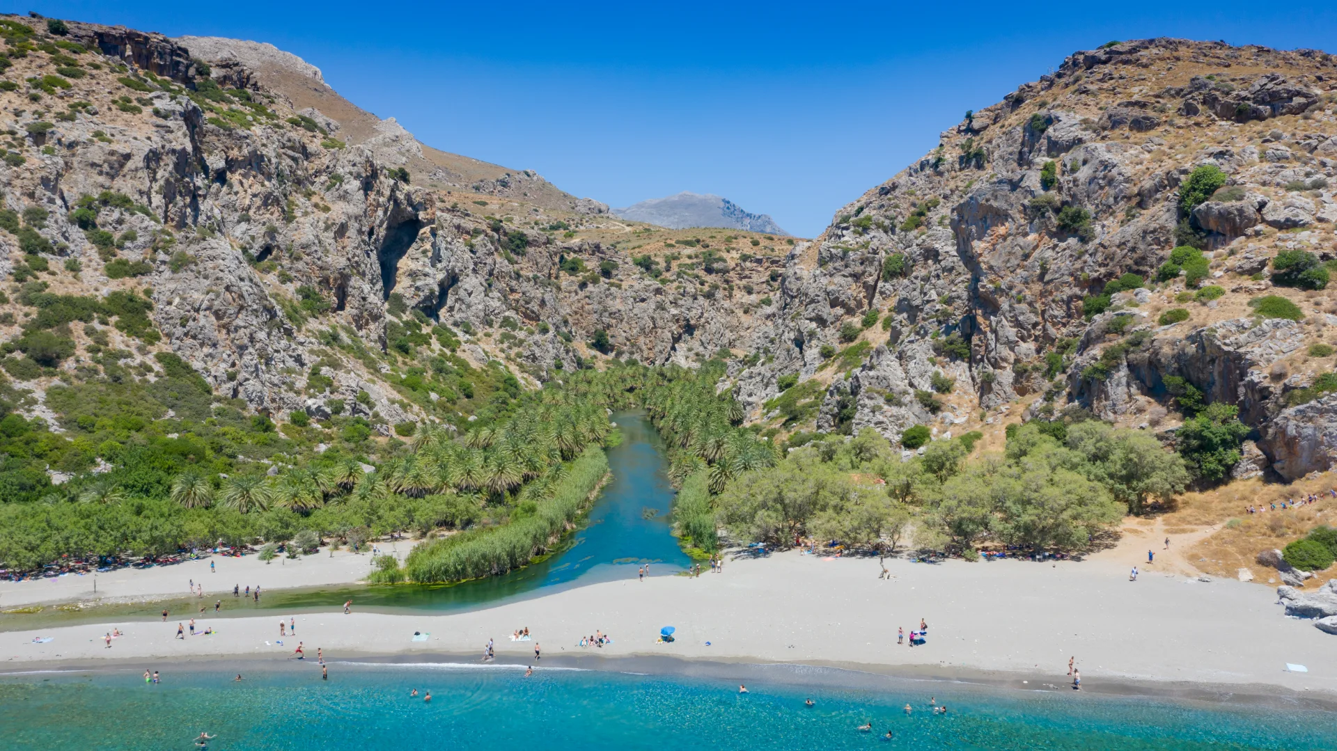 View of Preveli Beach with the river, palm grove and gorge behind it